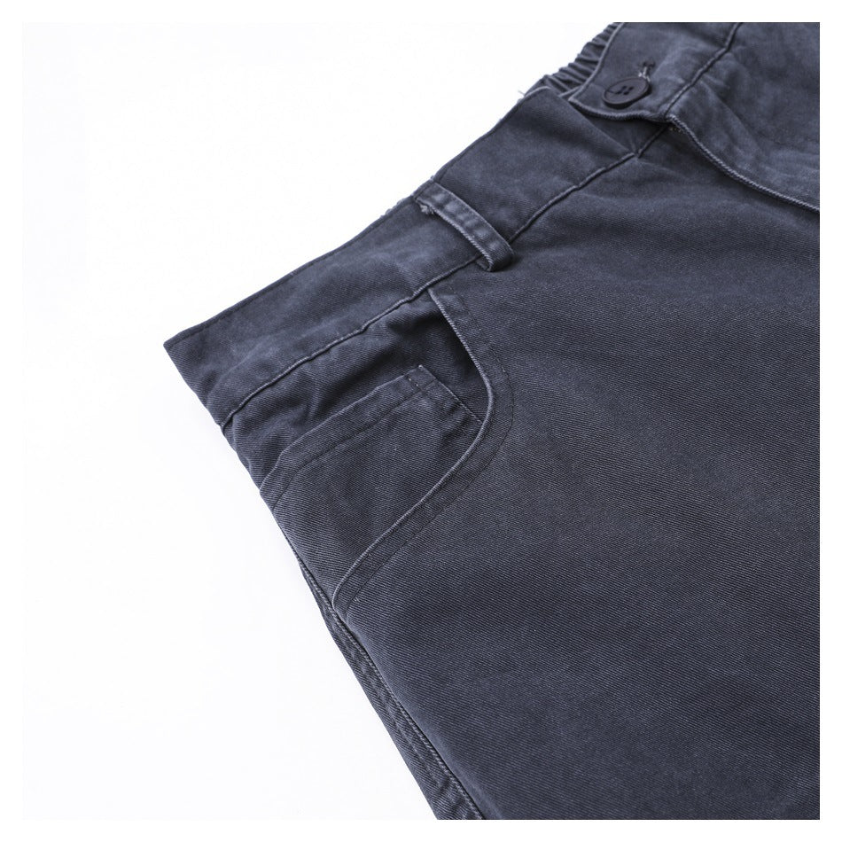 Angled close-up of charcoal trousers showing a front pocket, belt loop and buttoned waistband.