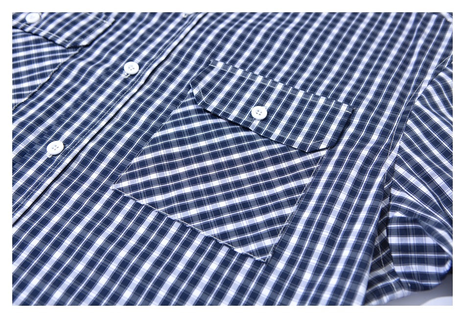 Close-up of a navy, white, and gray plaid shirt showing its button placket and chest pocket.