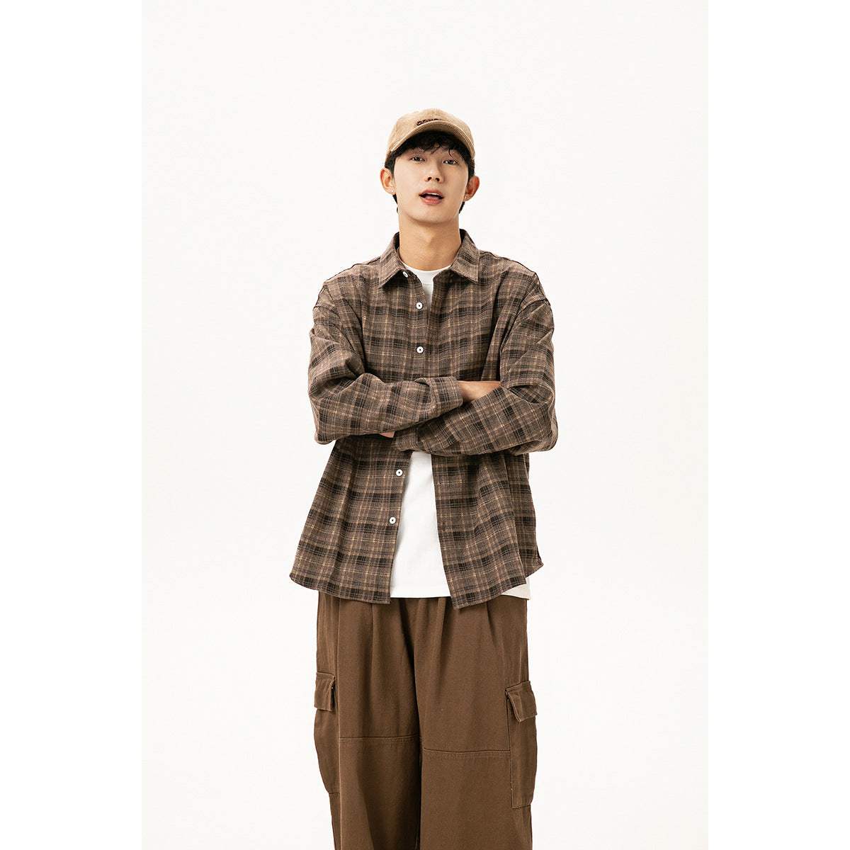 Model wearing an oversized brown plaid button-up shirt over a white tee with brown cargo pants.