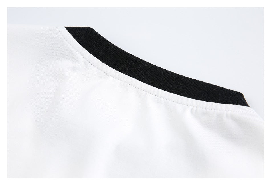 Close-up of a white shirt with black ribbed collar trim and visible neckline stitching.