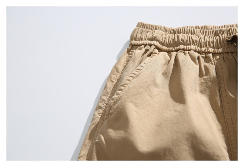 Close-up of the tan shorts' elastic waistband and angled front pocket.
