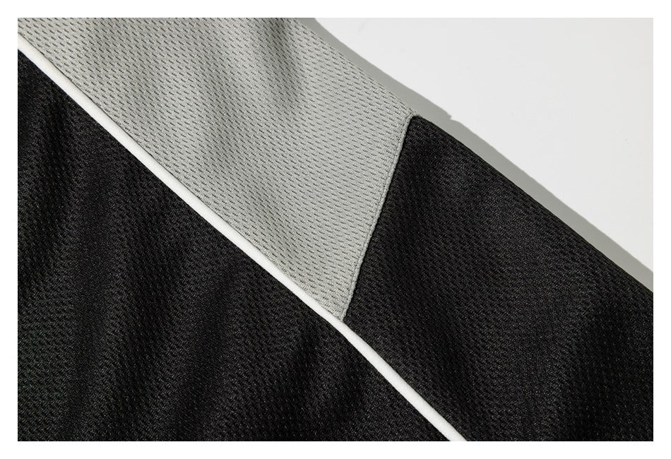 Close-up of black and light gray garment panels joined by narrow white piping.