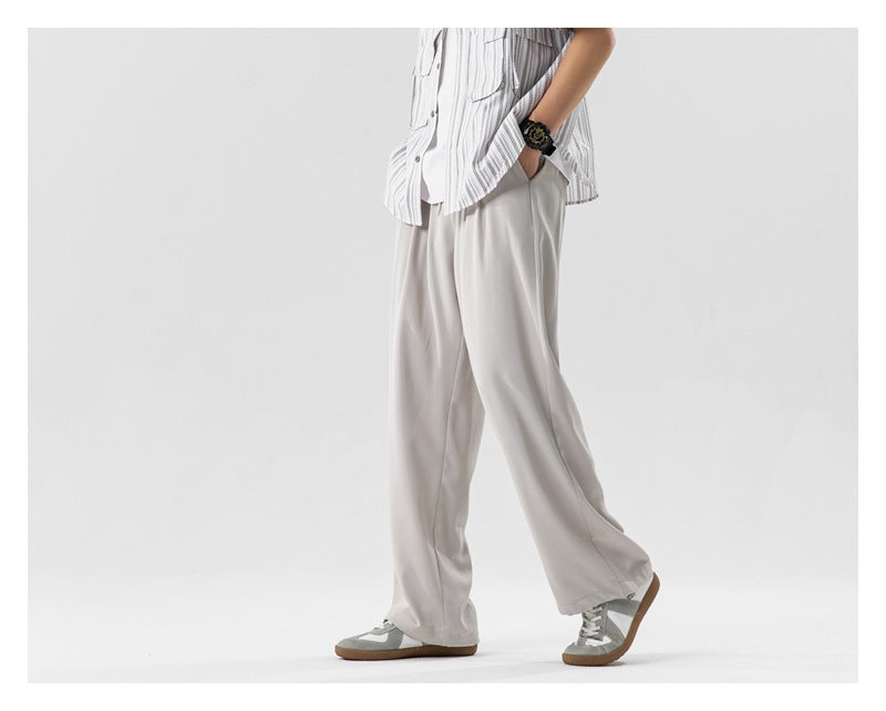 A person models pale gray wide-leg trousers with sneakers, shown in a cropped side view.