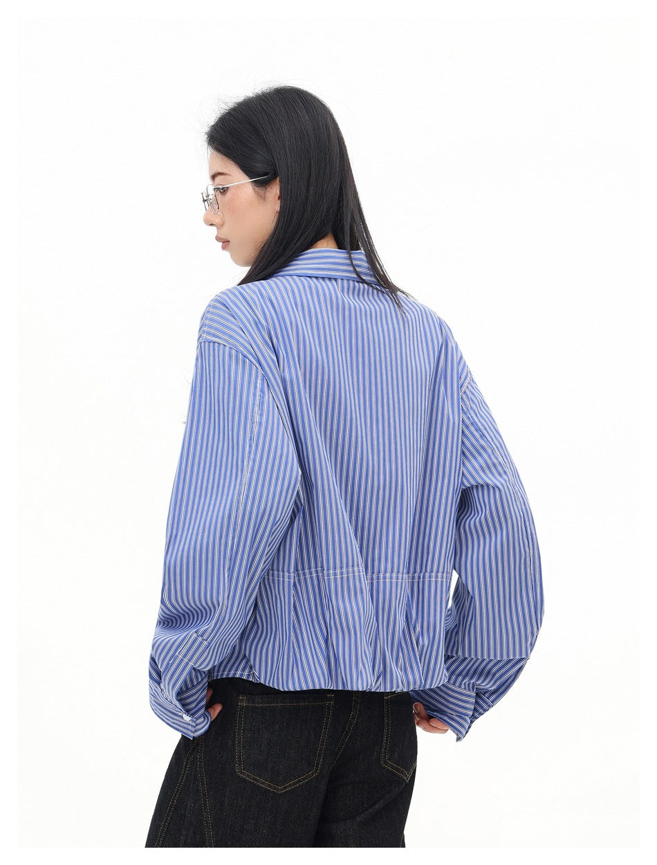 Rear view of a model wearing a blue and white pinstriped shirt with a gathered hem.