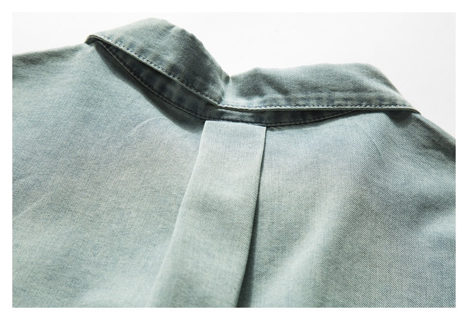 Close-up of the denim collar and center back seam on a light blue garment.