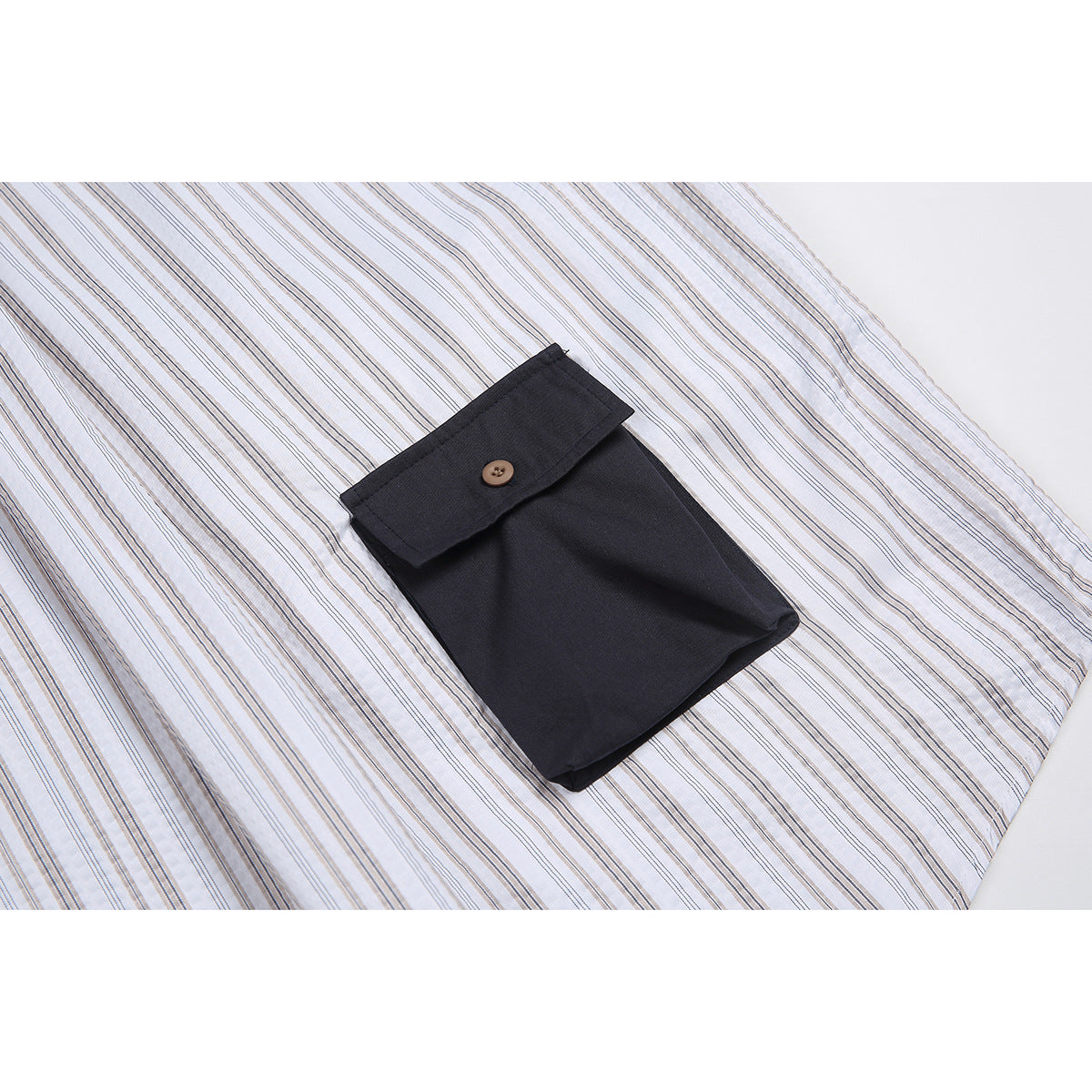Close-up of a dark button-flap pocket on the white shirt with fine gray and tan stripes.