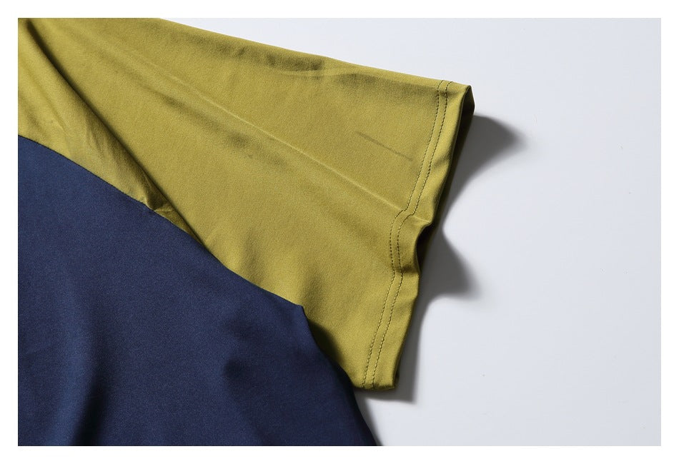 Close-up of a mustard sleeve with double-stitched hem beside a navy color-block panel.