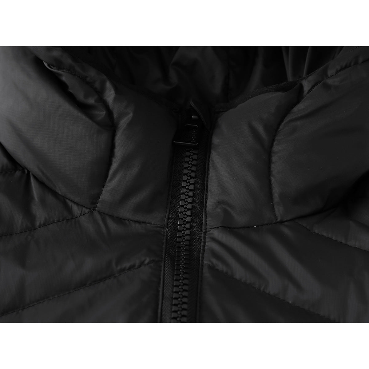 Close-up of the black jacket's chunky front zipper and quilted panels.