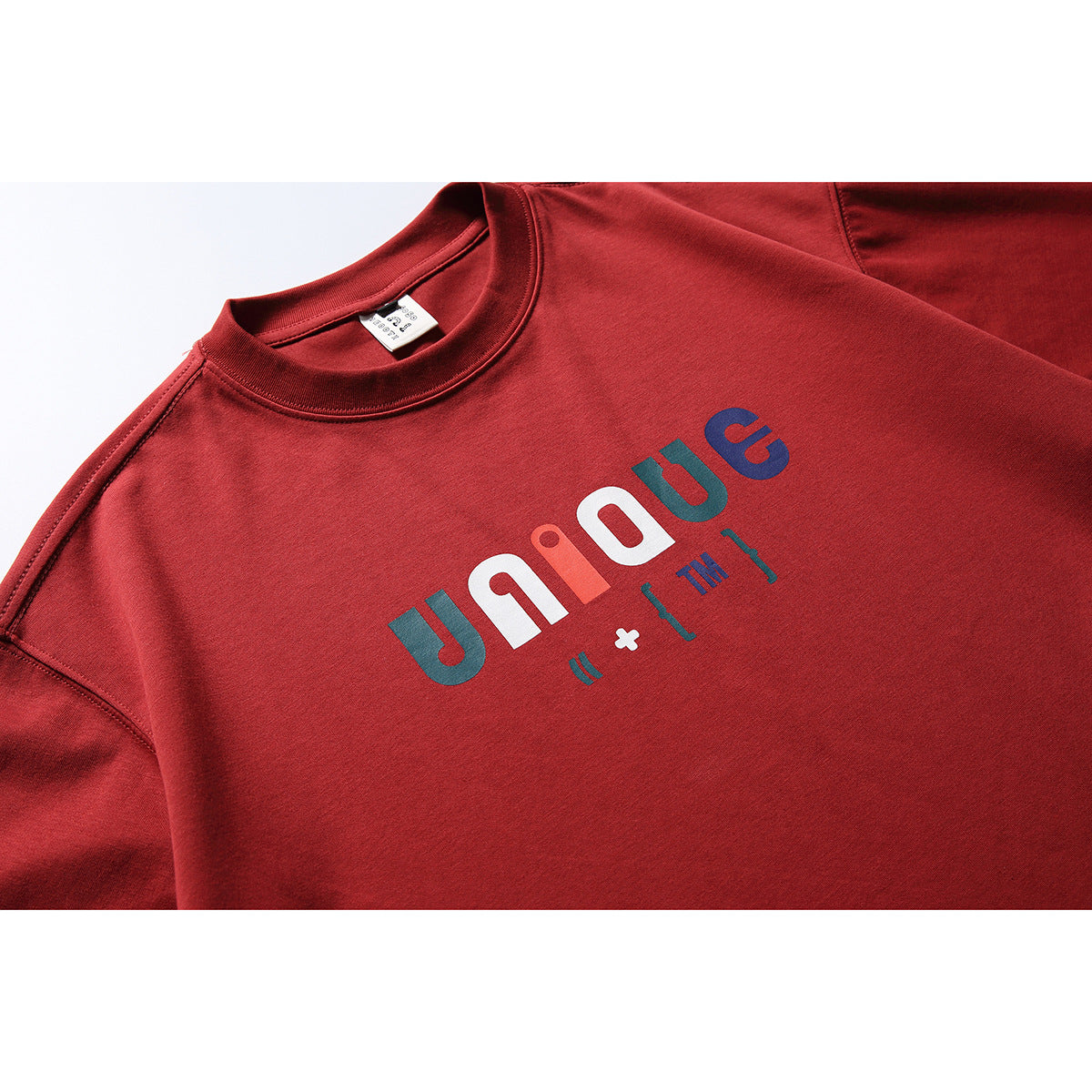 Close-up of a red crew-neck T-shirt with a multicolored graphic across the chest.
