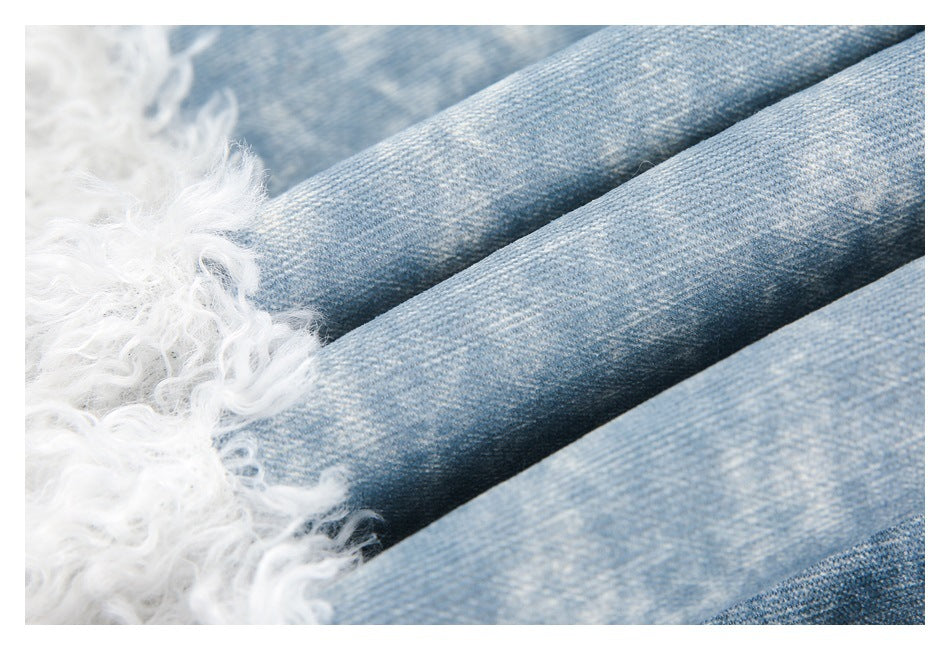 Close-up of folded light blue denim fabric beside white curly trim.