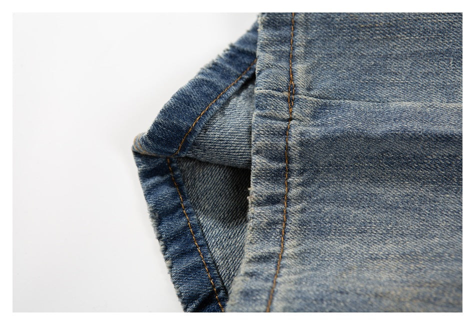 Close-up of blue denim fabric with a folded edge and contrasting tan stitching.