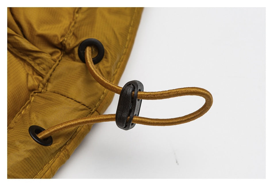 Close-up of a mustard-gold jacket drawcord threaded through black eyelets and an adjustable black toggle.