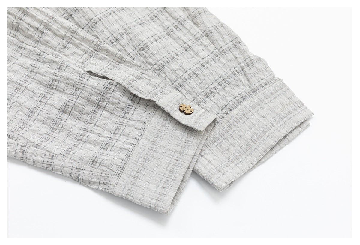 Close-up of the light gray checked shirt sleeve cuff with a decorative button.