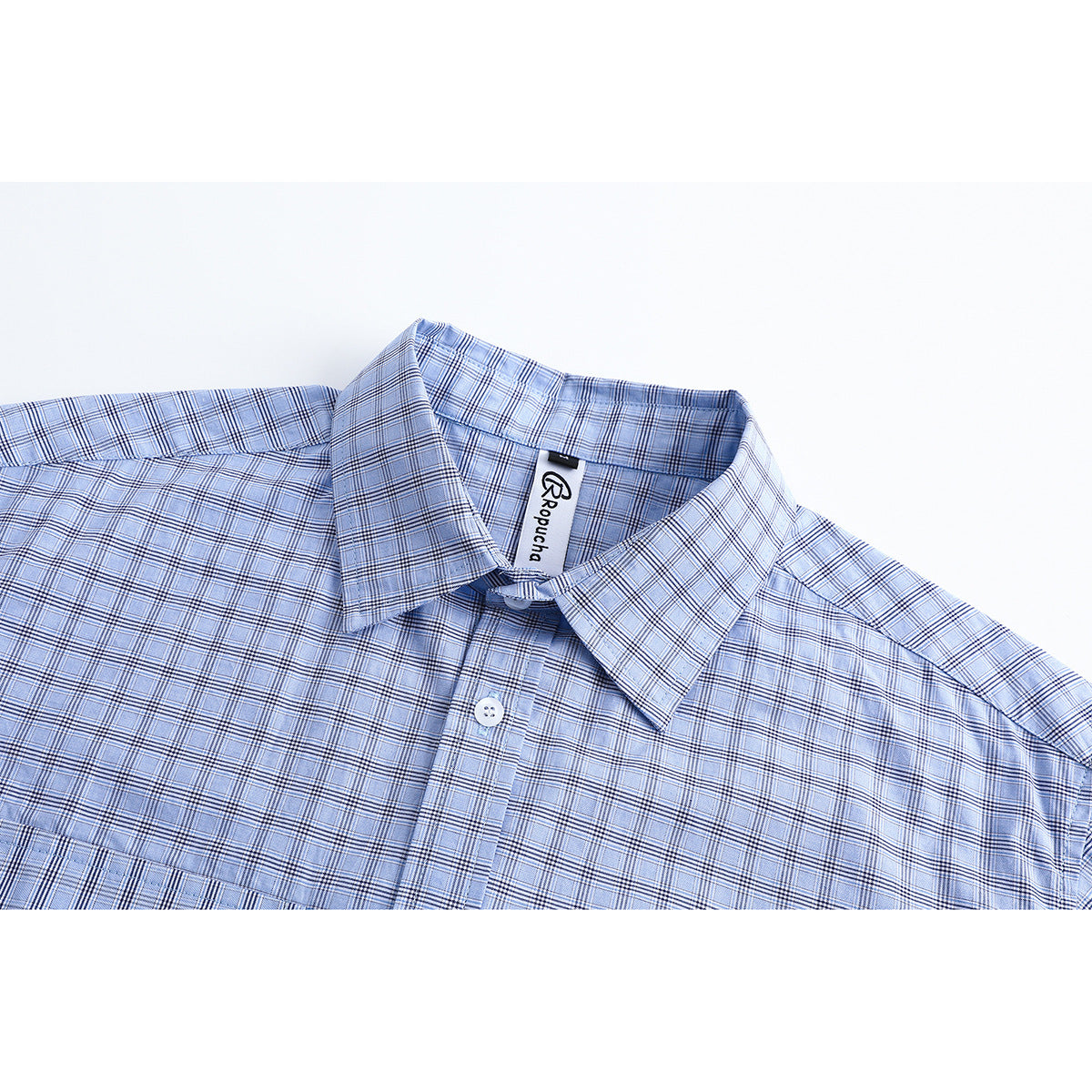 Close-up of a light blue plaid button-up shirt showing its pointed collar, placket, and inner neck label.