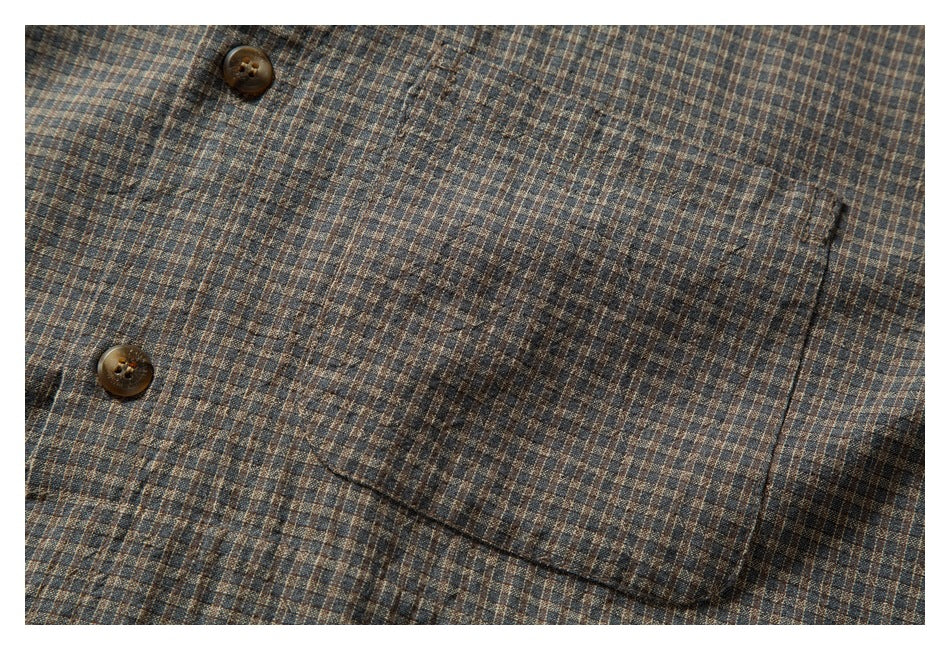 Close-up of a patch pocket, stitching, and buttons on a brown and blue small-check shirt.