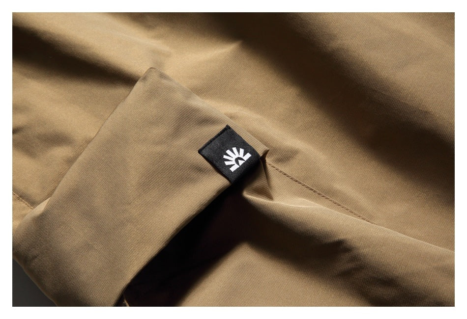 Close-up of a tan pants pocket seam and a small black fabric tab with a white emblem.