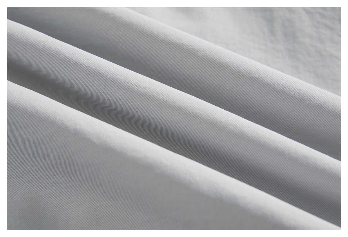 Macro view of light gray fabric folded to show its fine ribbed texture.