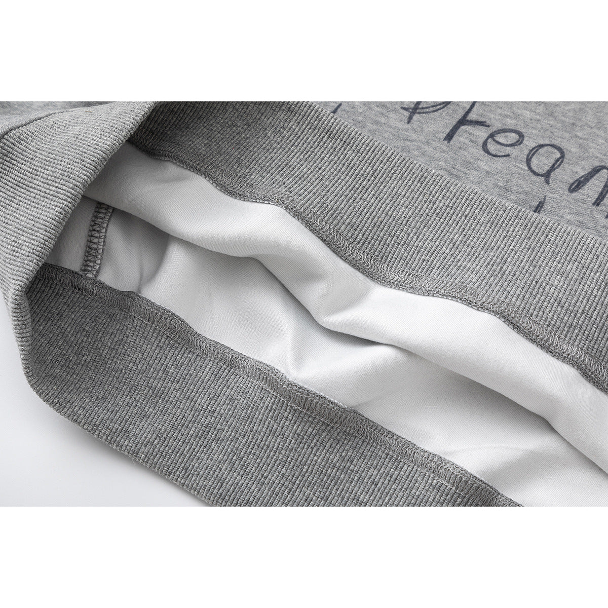 Close-up of a gray sweatshirt's ribbed hem and interior showing the seam finish and white inner surface.