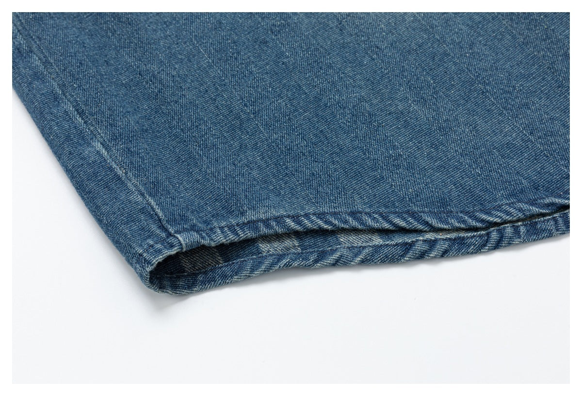Close-up of the folded hem edge of a blue denim garment against a white background.