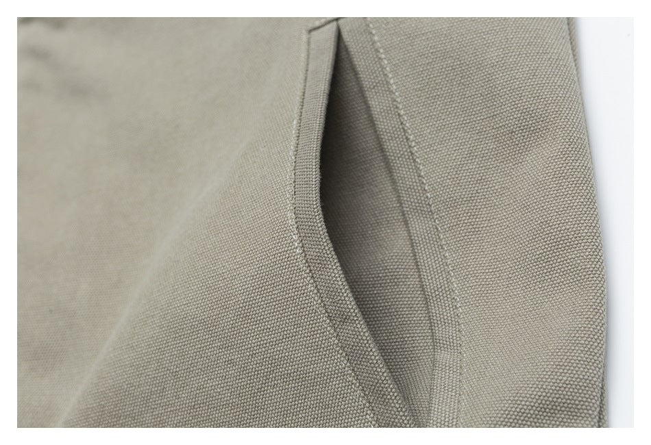 Close-up of a vertical slit pocket opening and stitching on a beige textured jacket.