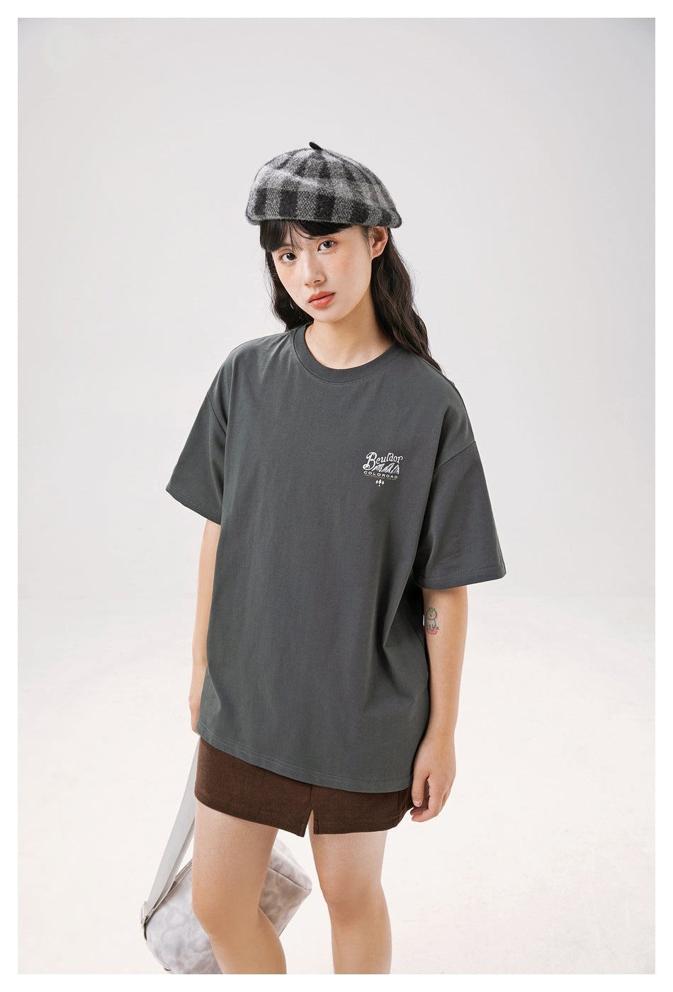 Closer front view of a model in an oversized charcoal gray T-shirt with a small white chest print.