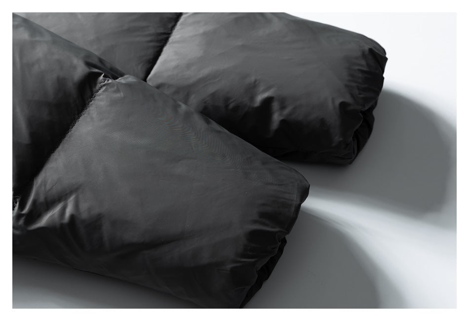 Close-up of two black padded garment sections with smooth fabric and stitched edges.
