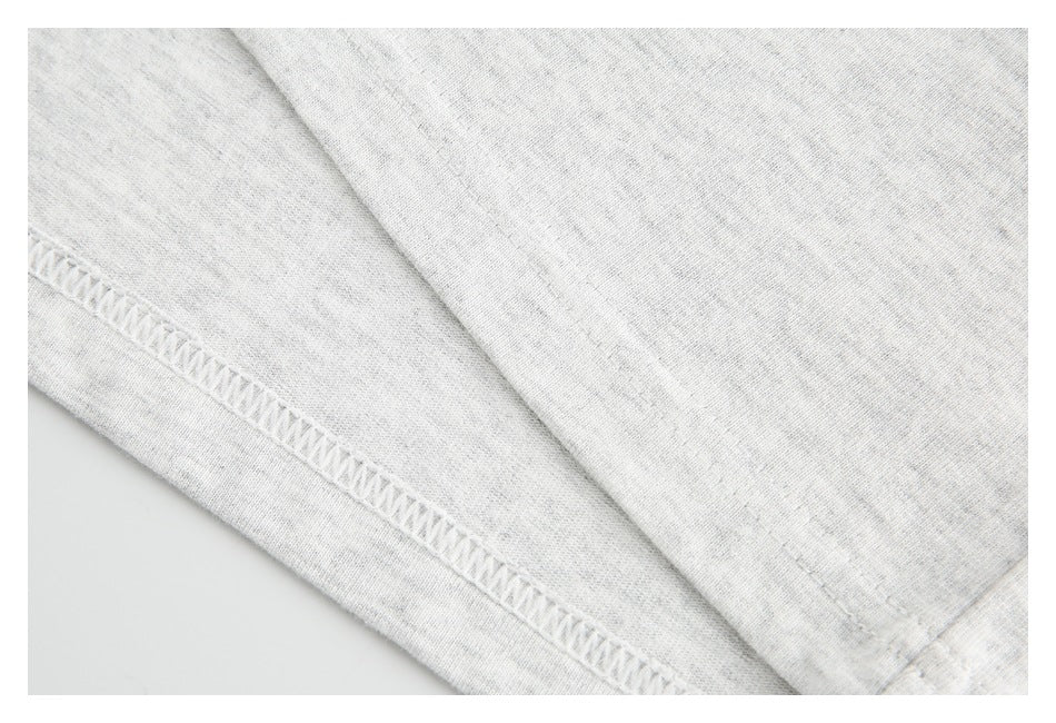 Close-up of light gray heathered fabric with a diagonal seam and overlock stitching.