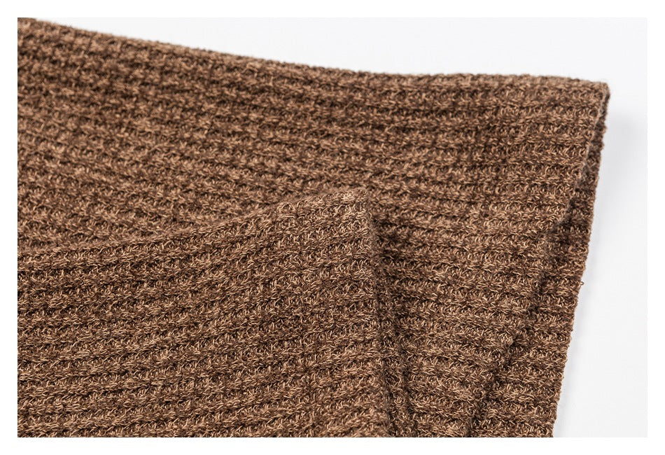 Close-up of a brown cardigan's ribbed knit edge and folded cuff.