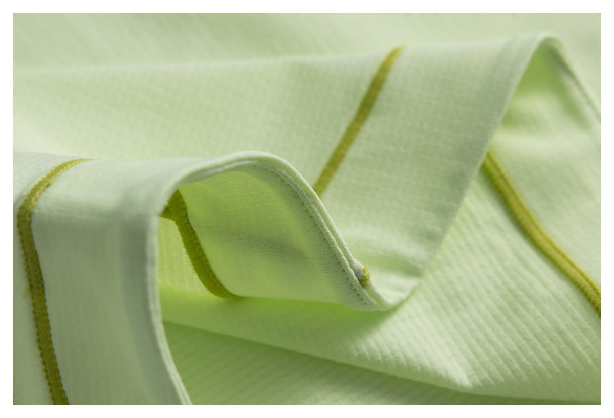 Close-up of pale lime fabric folds with yellow-green seam piping and stitching.