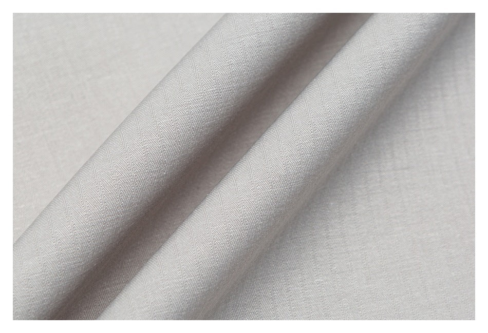 Close-up of pale gray fabric showing a subtle herringbone weave and soft folds.