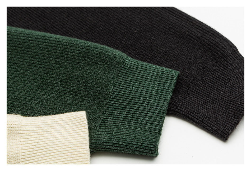 Close-up of ribbed sweater cuffs in black, dark green and cream.