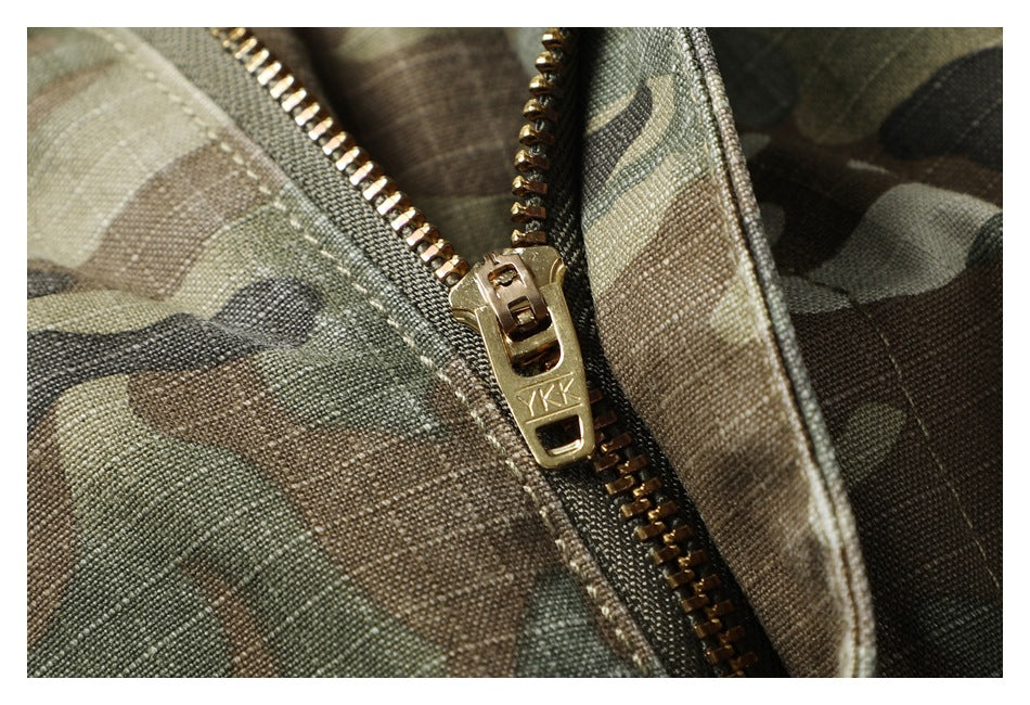Macro view of the brass-colored zipper and pull on olive camouflage pants.