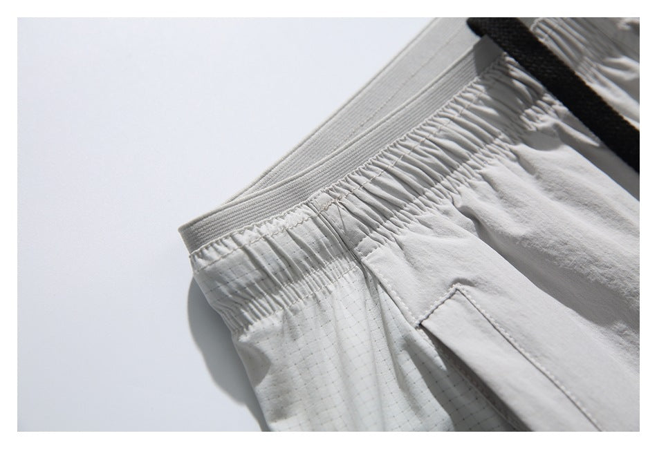 Detail of the gathered elastic waistband and subtle grid-patterned panel on light gray shorts.
