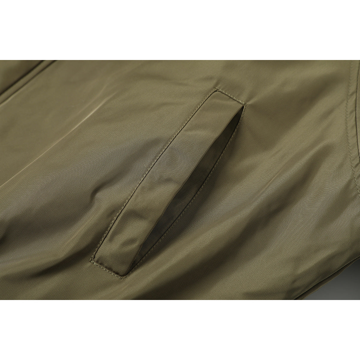 Close-up of a slanted welt pocket on olive jacket fabric.