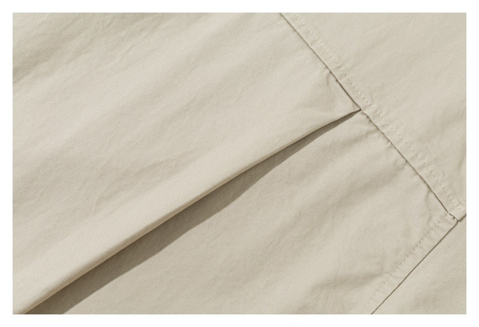 Close-up of beige garment fabric with overlapping panels and a prominent diagonal seam.