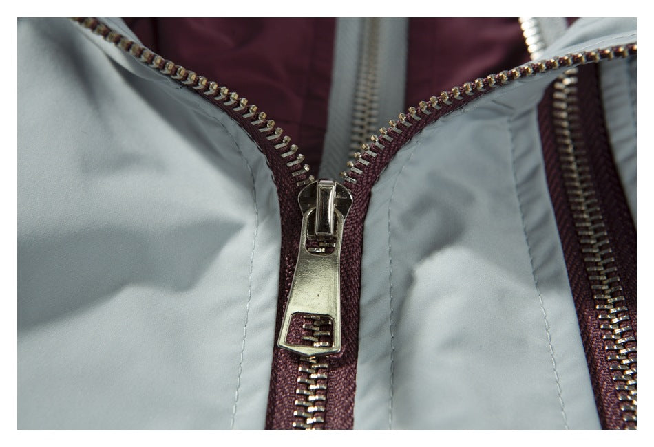 Close-up of a silver zipper and burgundy zipper tape between pale blue-gray vest panels.