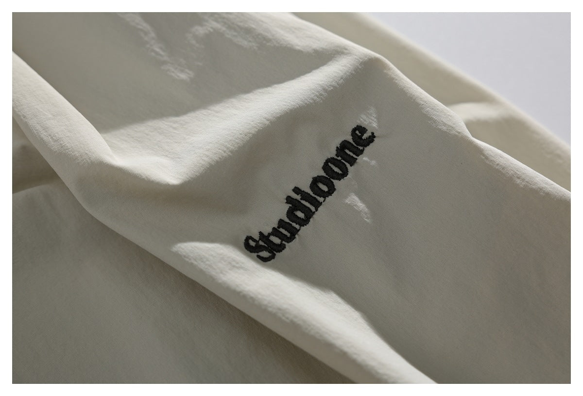 Close-up of black embroidered English lettering on light ivory shorts fabric.