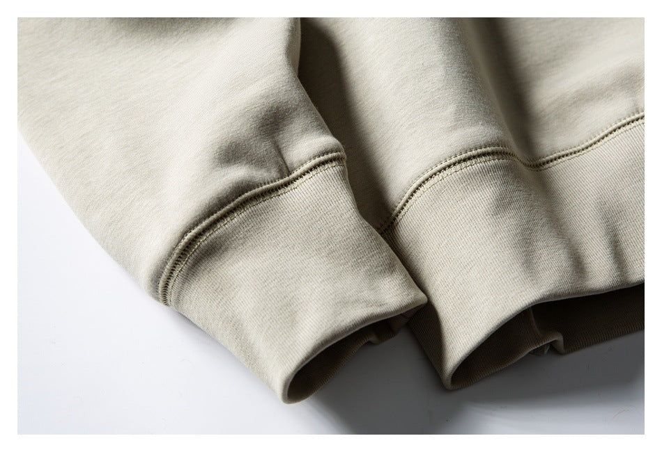 Close-up of a light beige sweatshirt sleeve ending in a ribbed cuff with visible stitching.