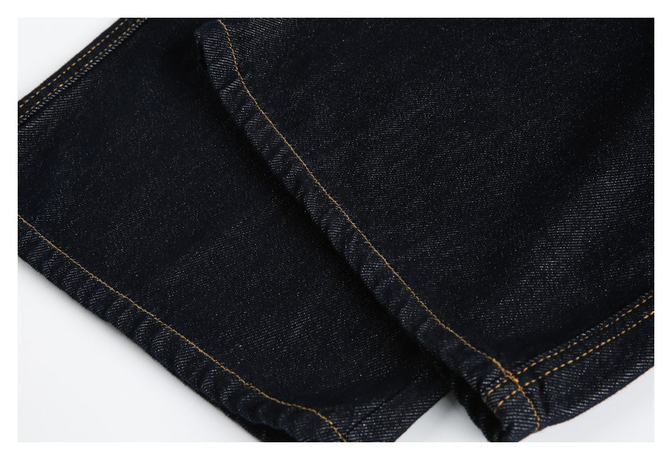Close-up of dark indigo jeans showing leg seams and stitched hems.