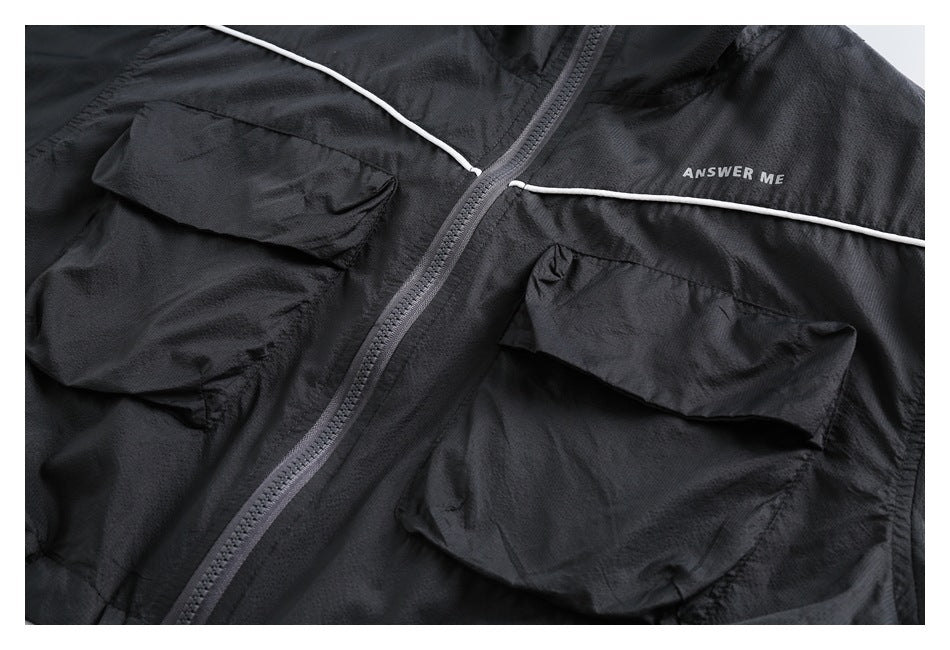 Close-up of a black jacket front with gray zipper, white piping, flap pockets, and small ANSWER ME lettering.