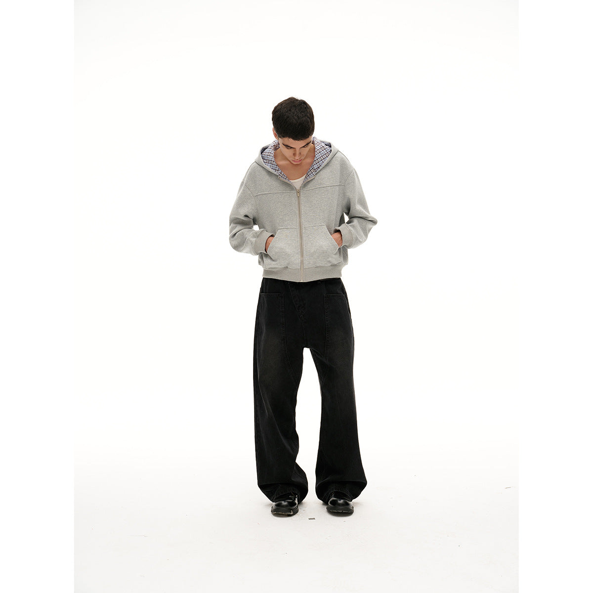 Full-length model wearing a light gray zip-up hoodie with plaid hood lining and wide black pants.