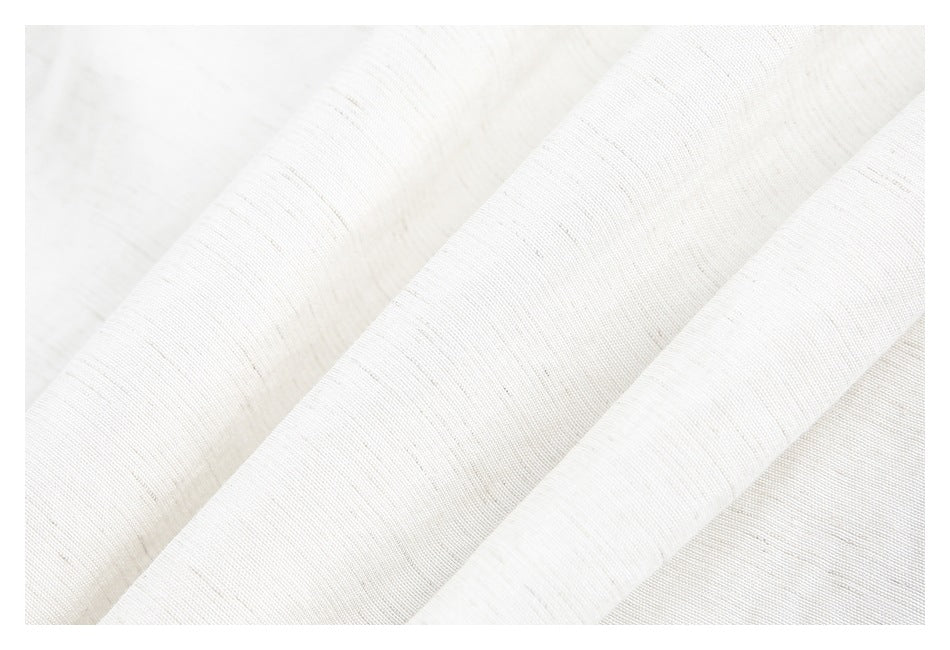 Close-up of off-white fabric draped in folds, showing its fine, subtly slubbed texture.