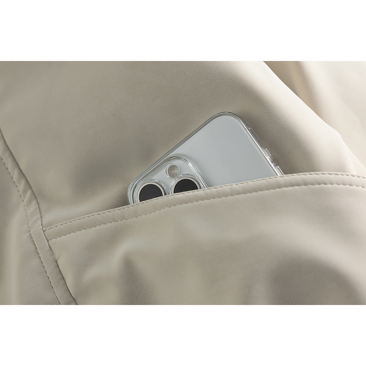 Close-up of an ivory jacket pocket holding a smartphone, showing the pocket seam and smooth surface.