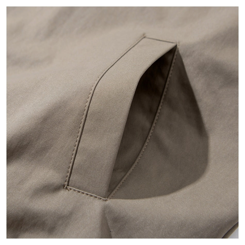 Close-up of a taupe garment's angled welt pocket with neat stitching.