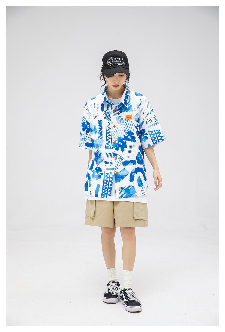 Front view of a model in a white short-sleeve button-up shirt with blue abstract prints and orange buttons.