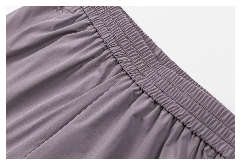 Close-up of mauve-gray shorts showing a wide, gathered elastic waistband and pleated fabric.