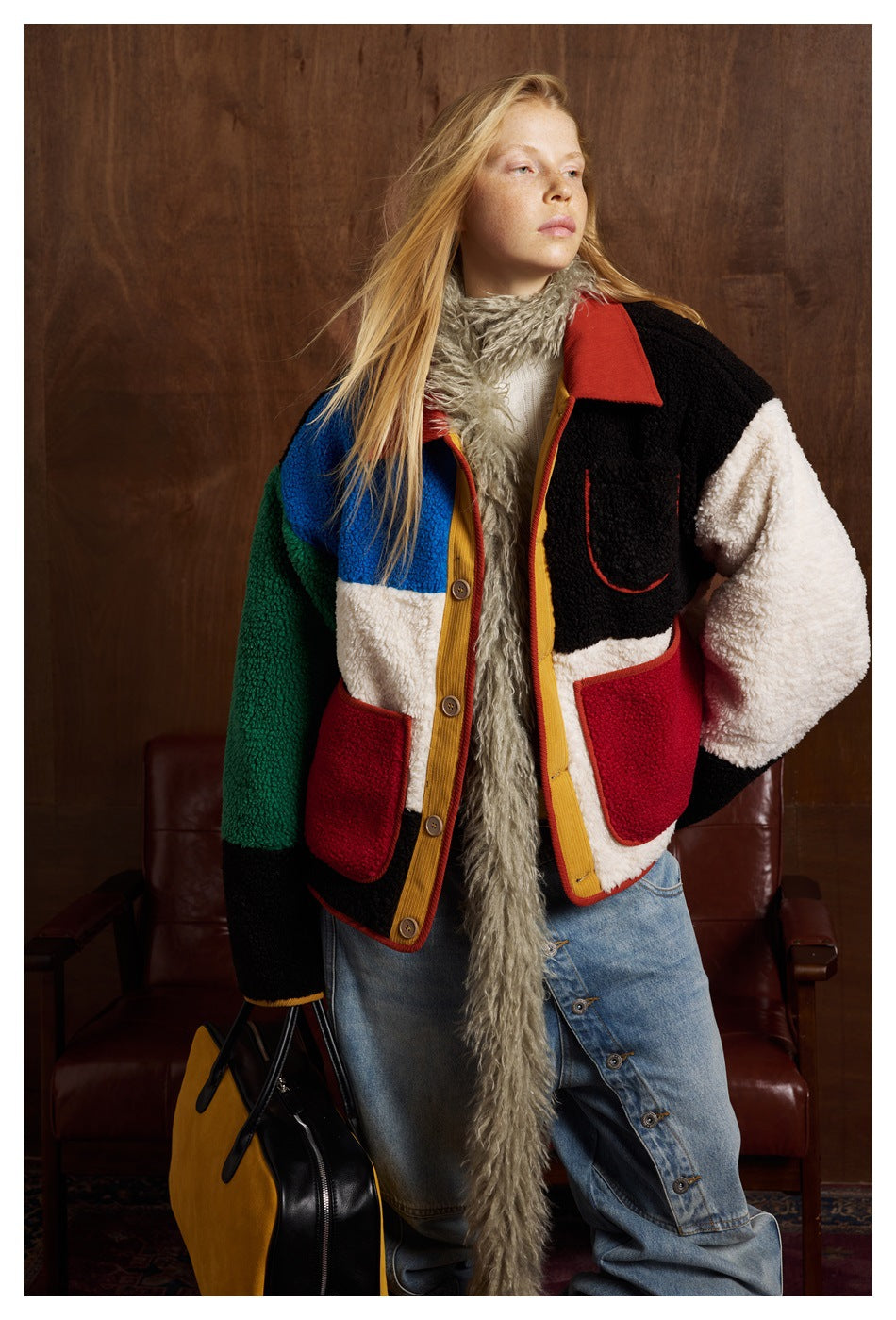 Model wearing a color-block fleece jacket with contrasting sleeves, red pockets and a button front.