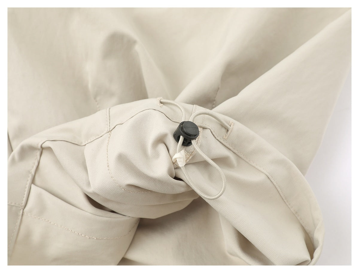 Close-up of beige shorts’ adjustable drawcord waist with a black toggle and stitched seams.