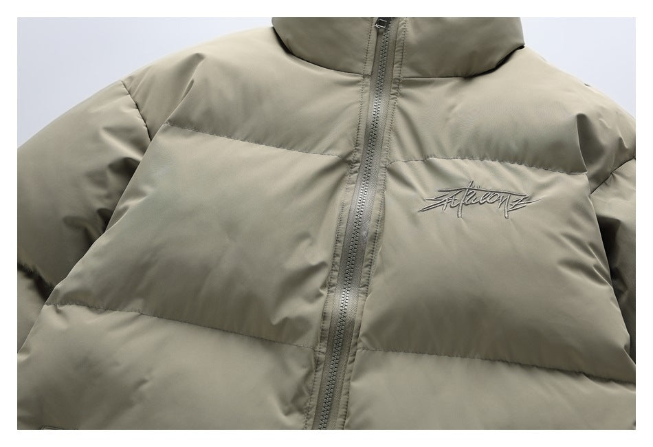 Close-up of an olive-khaki puffer jacket front with a central zipper and embroidered script on the chest.