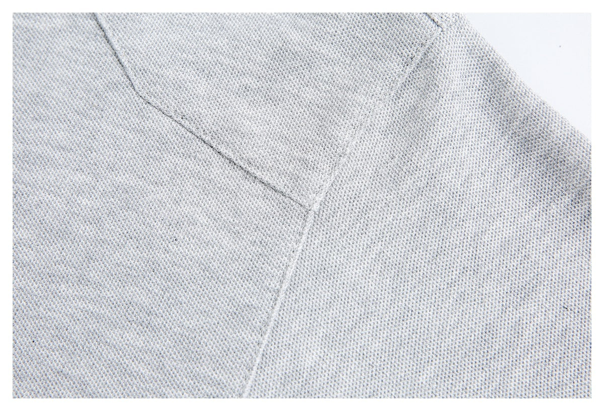 Close-up of light gray knit fabric with intersecting stitched seams.